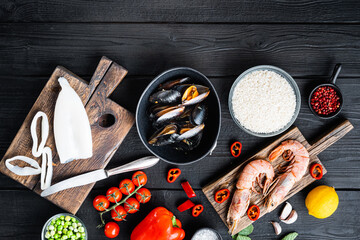 Fresh uncooked sea food specialties and rice with mussels, shrimps and squid on black wooden background, flat lay with copy space