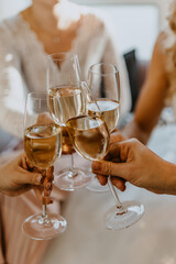 Funny and beautiful girls hold in hands glasses with yellow champagne, best friends celebrating and toasting or wedding day.