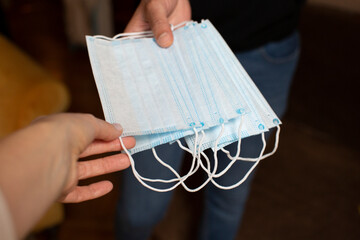 hands of two people handing out hygienic masks