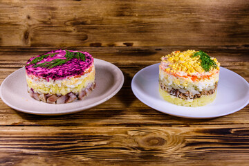 Traditional russian new year layered salads Mimosa and Herring under a fur coat (shuba) on wooden table