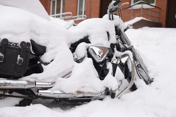 Winter in Russia. Abandoned motorcycle covered with a thick layer of snow