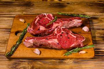 Raw ribeye steak, spices, rosemary and garlic on cutting board