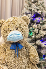 Coronavirus quarantine concept, teddy bear in a protective mask on the background of a christmas...