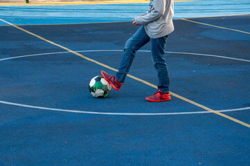 boy with a ball on the mini-football field foot on ball the football player is preparing to hit the ball