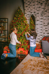 Two pretty women close up under the festive fir-tree indoors with the boxes of gifts.Christmas photo