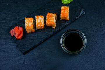 Sushi roll philadelphia with salmon, rice, cheese, cucumber, avocado and caviar on a slate board. Japanese food. Top view