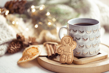 Beautiful cup with handmade gingerbread boy on a cozy blurred background with lights.