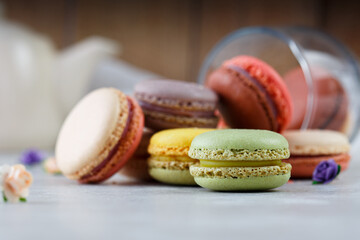 Colorful macarons on white table and wooden background
