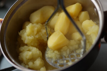 potatoes being mashed in stainless steel saucepan close up