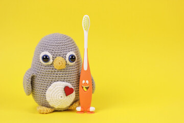 Pretty baby scene with handmade knitted toy.Crochet Amigurumi penguin toy with toothbrush on yellow background.Great for small businesses, children bloggers, social network pages, stores, websites.