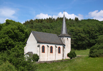 Fototapeta na wymiar Landscape with baroque Walholzkirche church with romanesque bell tower on a meadow near Hunolstein village, Hunsrück mountains in Germany