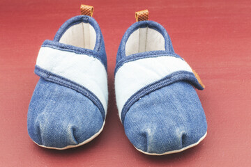 Baby shoes on red background.