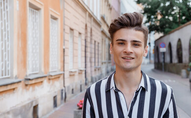 Young hipster man outdoors. Image of happy young man walking on the street and looking aside while. The guy on the street and looking at camera. Poland.