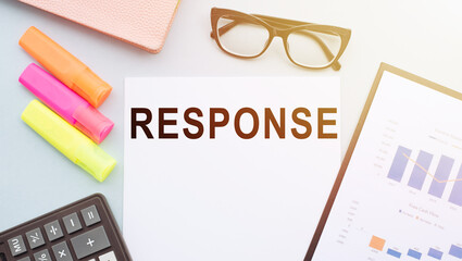 The text RESPONSE on office desk with calculator, markers, glasses and financial charts.