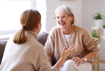 Mother and daughter laughing at joke on sofa.