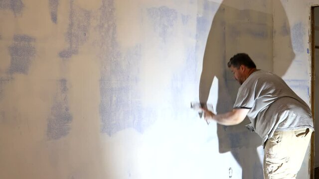 Worker puttied wall using a paint spatula hand worker repairs gypsum plasterboard