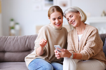 Happy mother and daughter using smartphone together.