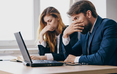 Business men and woman sit at a work table in front of laptop emotions office
