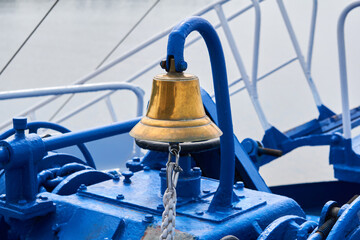 brass bell on the foredeck of a ship in cloudy light