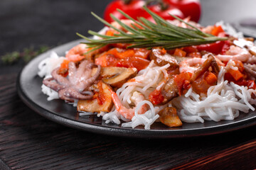 Tasty rice noodles with tomato, red pepper, mushrooms and seafood