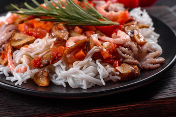 Tasty rice noodles with tomato, red pepper, mushrooms and seafood