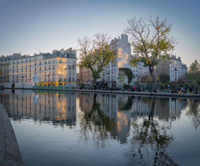 Fototapeta na wymiar Paris, France - 12 28 2019: Reflections of buildings at the Canal Saint-Martin at sunset