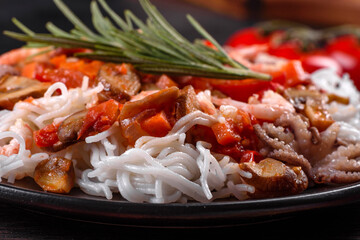 Tasty rice noodles with tomato, red pepper, mushrooms and seafood