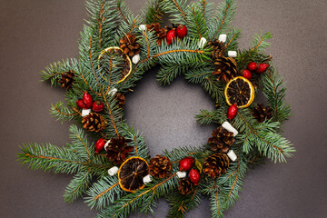 Fototapeta na wymiar Zero waste Christmas wreath with fir tree branches, rosehip berries, lemon slices and marshmallows