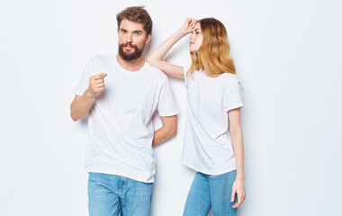 A guy and a beautiful woman in the same clothes on a light background are gesticulating with their hands 