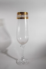 glass with golden ornament on white table casts shadow