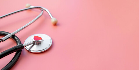 Black stethoscope with red heart of doctor for checkup on pink background. Stethoscope equipment of medical use. Health care and cardiology concept with copy space. Valentines day