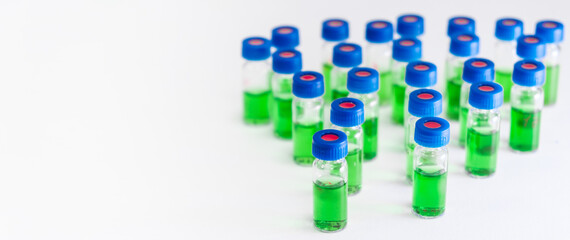 Obraz premium Green samples in HPLC vials on the white background on the white background with copy space. Herbal extract for developing of natural drugs