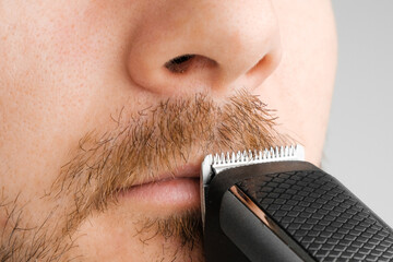 Shaving of mustache with electric razor or trimmer with copy space.
