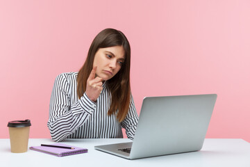 Be careful! Bossy woman office worker in striped shirt looking at laptop screen and warning finger, giving advice on video call, online conference. Indoor studio shot isolated on pink background