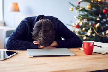 Tired man lying on desk while working from home during Christmas