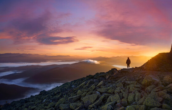 Silhouette of a girl on a mountain peak in the morning at sunrise.
