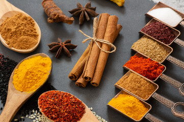 Various spices in spoon or bowl on dark rustic table, spice background