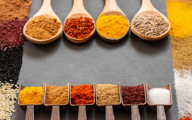 Various spices in spoon or bowl on dark rustic table, spice background