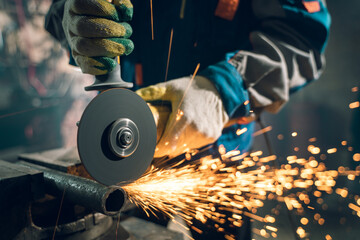 Locksmith in special clothes and goggles works in production. Metal processing with angle grinder....