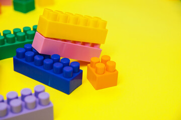 Constructor details are scattered on a yellow background. Multi-colored construction blocks.