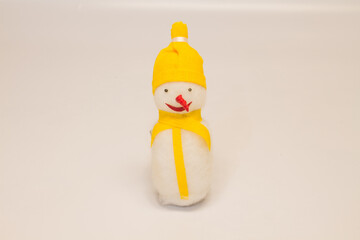 Christmas toy snowman with a red nose in a yellow hat and a scarf on a white background