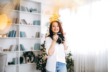 Happy New Year. Beautiful brunette waits and receives gifts near the Christmas tree