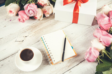roses with gift and notepad with cup of coffee