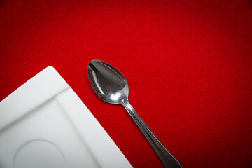Top view of plate and teaspoon on red background. Cutlery use concept.
