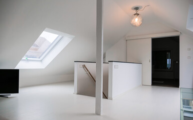 Moderner weisser Raum am Dachboden mit Holzbalken und Treppen in der Mitte