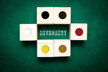 Wooden cubes with icons of different colors and the word DIVERSITY on a green background. Concept of equality and equality for people, diversity.