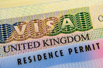 UK Biometrical Residence Permit (BRP) card placed on top of UK tourist visa sticker in a passport....