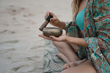 Hands holding mallet playing on a tibetian singing bowl in the morning, .(The Nepal word on the...