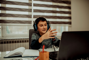 Boy attending online classes from home. Child using laptop and headsets for connecting with teacher and schoolmates. School education and social distance during quarantine