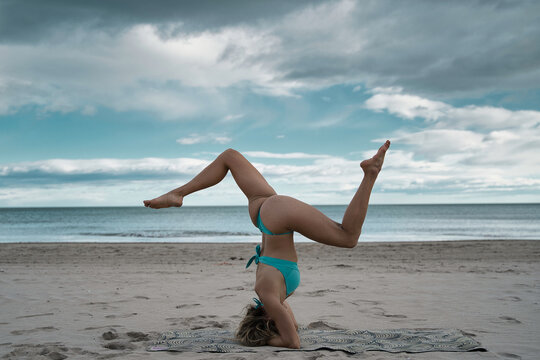 Young blonde yogi woman training in inverted body positions. 